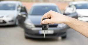 Hånd holder bilnøgle foran biler